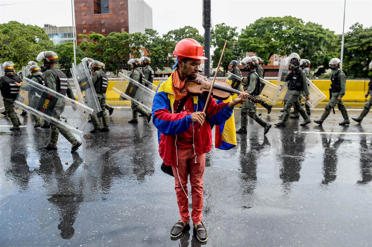 A Venezuelan man plays the violin as security forces march past
