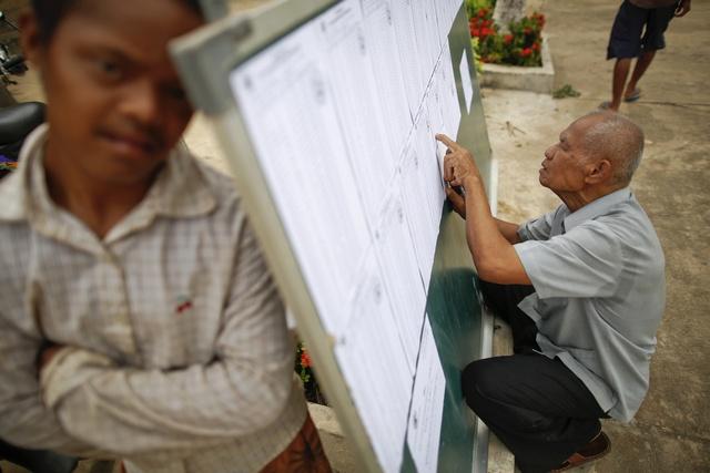 A man checks lists of voters at a polling station in suburbs of Phnom Penh, 2013