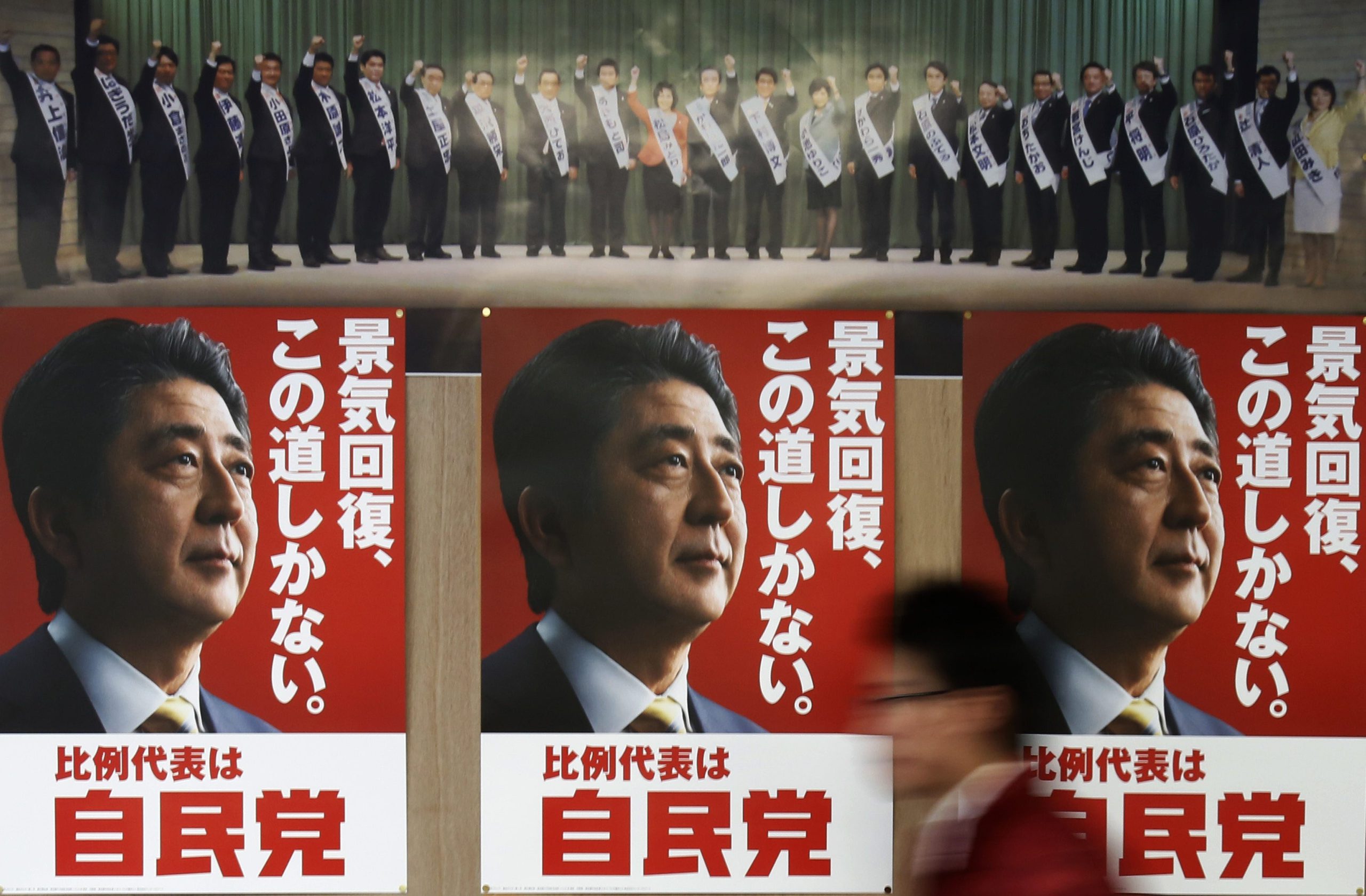 Staff member of Japan’s ruling Liberal Democratic Party walks past election campaign posters showing Japan’s Prime Minister Shinzo Abe at the LDP regional election office in Tokyo