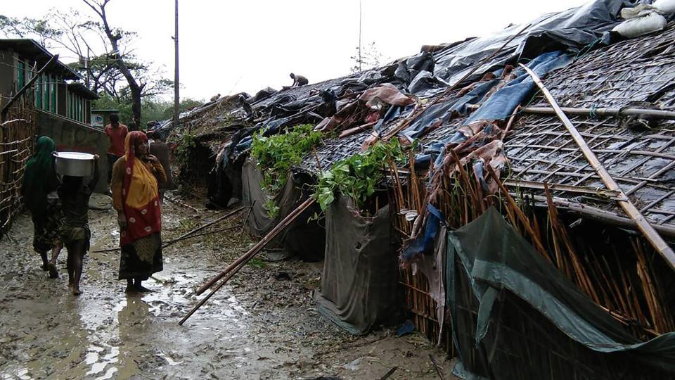 Rohingya refugees walk next to huts in a makeshift camp in Bangladesh's Cox's Bazar district on May 30, 2017 after Cyclone Mora made landfall in the region.