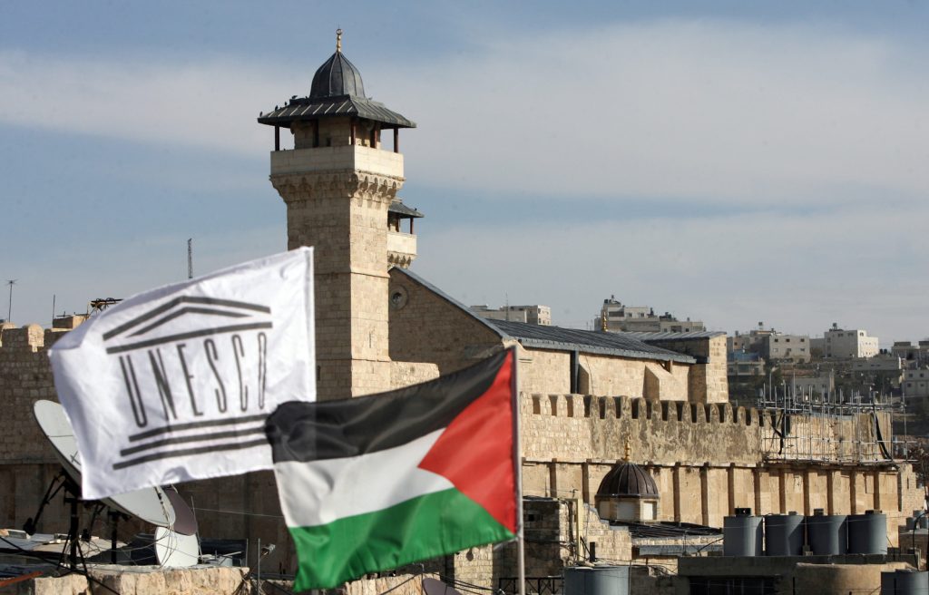The Palestinian Rehabilitation Committee raised the UNESCO flag next to the national Palestinian flag in front of Hebron's Ibrahimi Mosque or the Tomb of the Patriarchs in the southern West Bank city's old quarter on December 13, 2011, as the Palestinian flag was hoisted at the UNESCO headquarters in Paris, a month after the Palestinians' admission to the UN cultural agency sparked anger and reprisals from the United States and Israel.