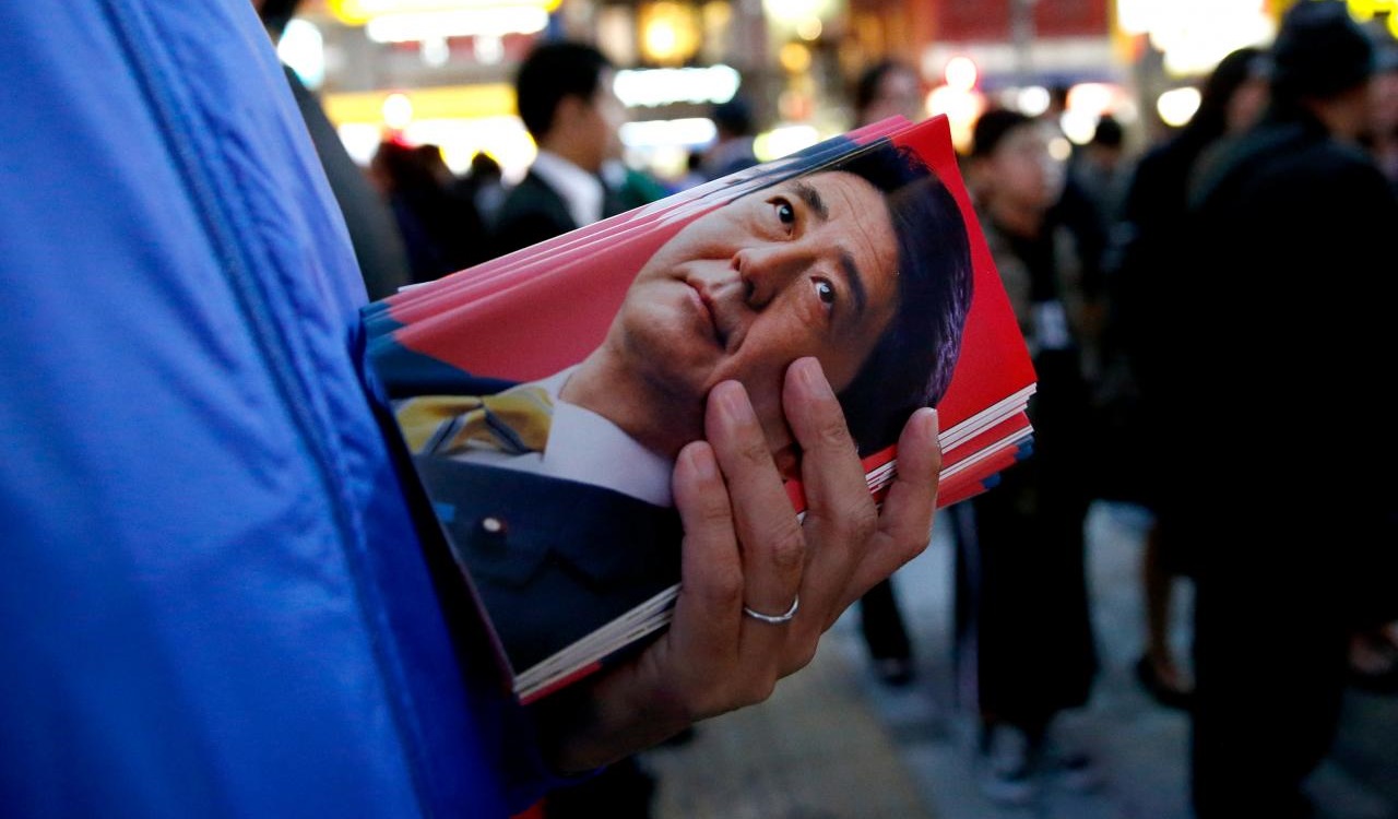 A man holds leaflets featuring an image of Japan's Prime Minister Shinzo Abe, who is also ruling Liberal Democratic Party leader, at a Japanese election campaign rally in Tokyo, Japan October 18, 2017.