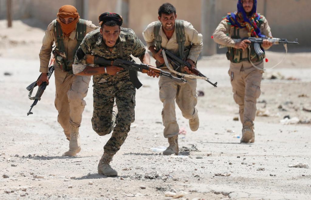 Kurdish fighters from the People's Protection Units (YPG) run across a street in Raqqa, Syria July 3, 2017.