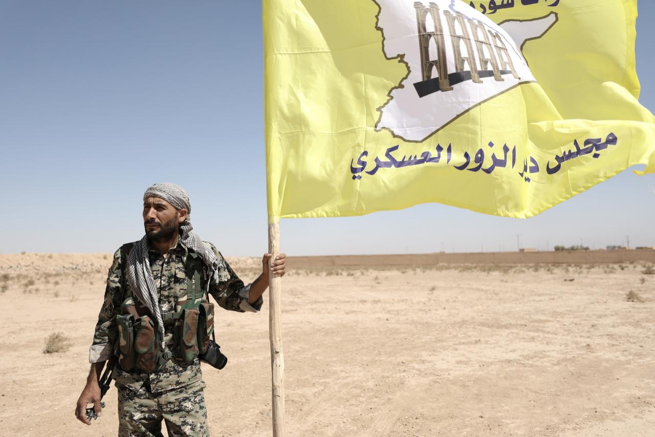 A fighter from Deir al-Zor military council which fights under the Syrian Democratic Forces (SDF) holds the council's flag in the village of Abu Fas, Hasaka province, Syria September 9, 2017.