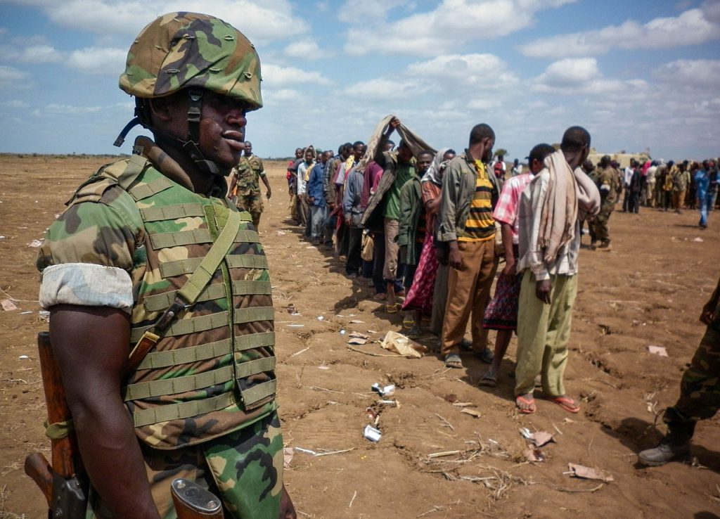 A Ugandan soldier of the African Union Mission in Somalia (AMISOM) looks on as members of the Al Qaeda-affiliated militant group Al Shabaab stand in line after more than 200 fighters gave themselves up to AMISOM forces of the in Garsale, approximately 10km from the town of Jowhar, 80km north of the capital Mogadishu, 22 September 2012 / Africa