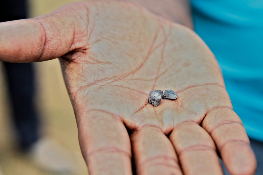 The foreman for a mining company holds up a fragment of cobalt in Mpaza. Cobalt mining has led to landslides blocking boreholes and damaging the water supply.