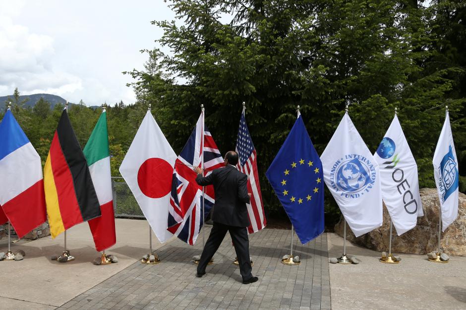 A delegate grabs a flag to prevent it from being blown over by the wind outside of the G7 Finance Ministers summit in Whistler