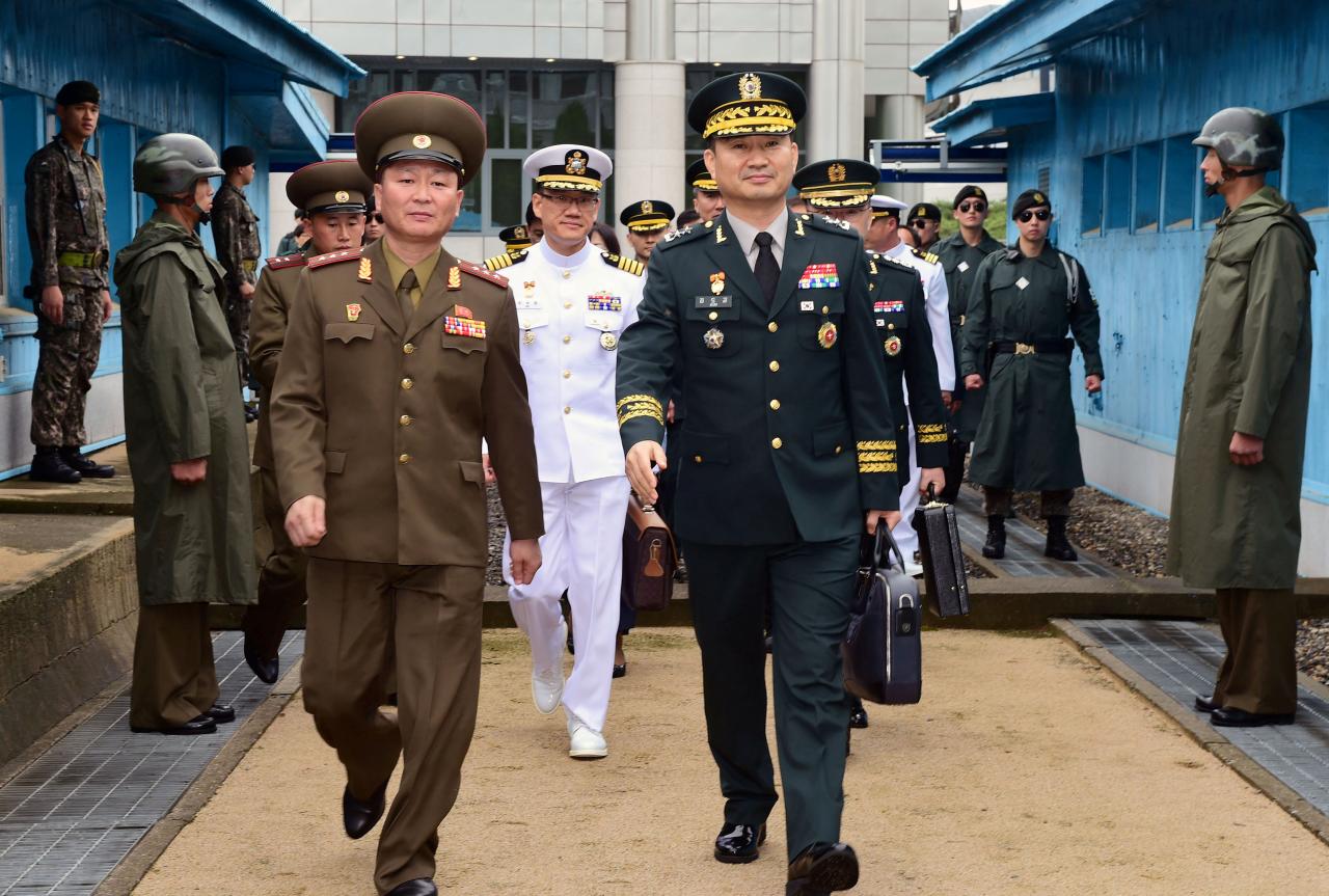 North and South Korean delegation walk as they cross the concrete border at the northern side of the truce village of Panmunjom