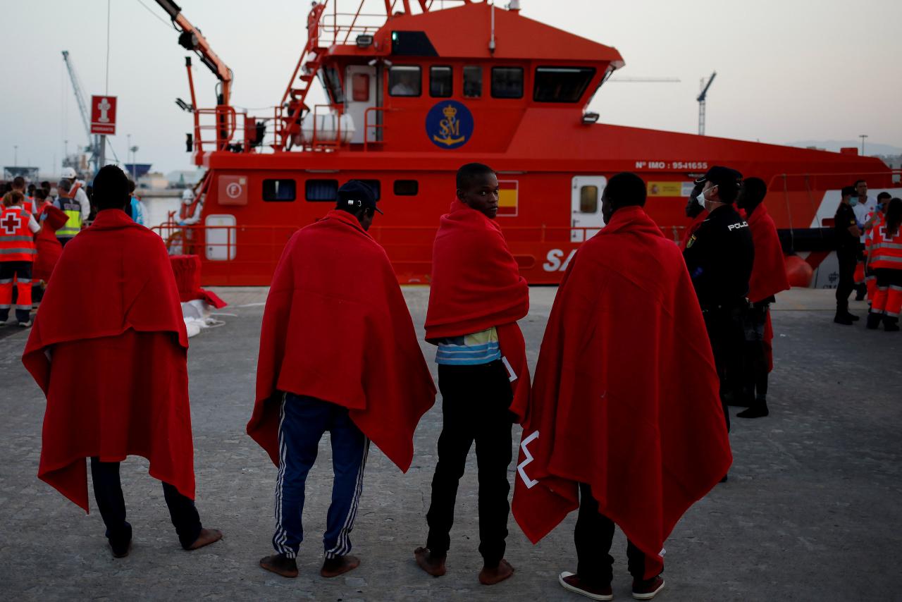 Migrants stand after arriving on a rescue boat at a port in Malaga