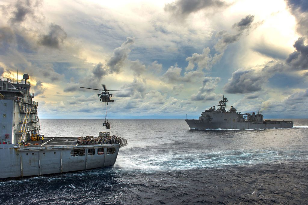 A U.S. Navy Sikorsky MH-60S Seahawk helicopter attached to Helicopter Sea Combat Squadron 21 (HSC-21) "Blackjacks" lifts pallets of supplies from the flight deck of the Military Sealift Command fleet replenishment oiler USNS Walter S. Diehl / NDAA