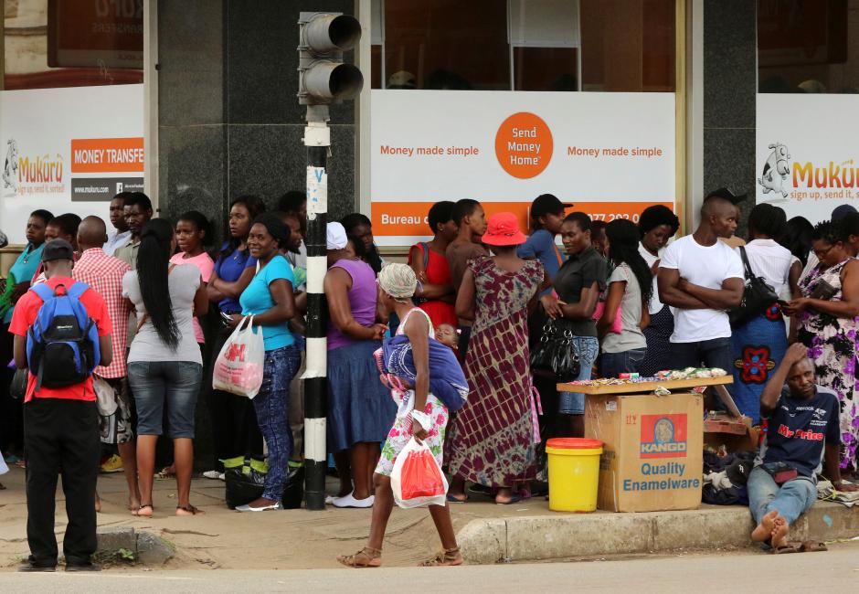 FILE PHOTO: People queue to withdraw money from a bank in Harare