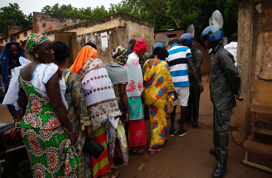 Security forces carry out checks as people wait at a polling station before the polls open for the presidential election in Bamako, Mali