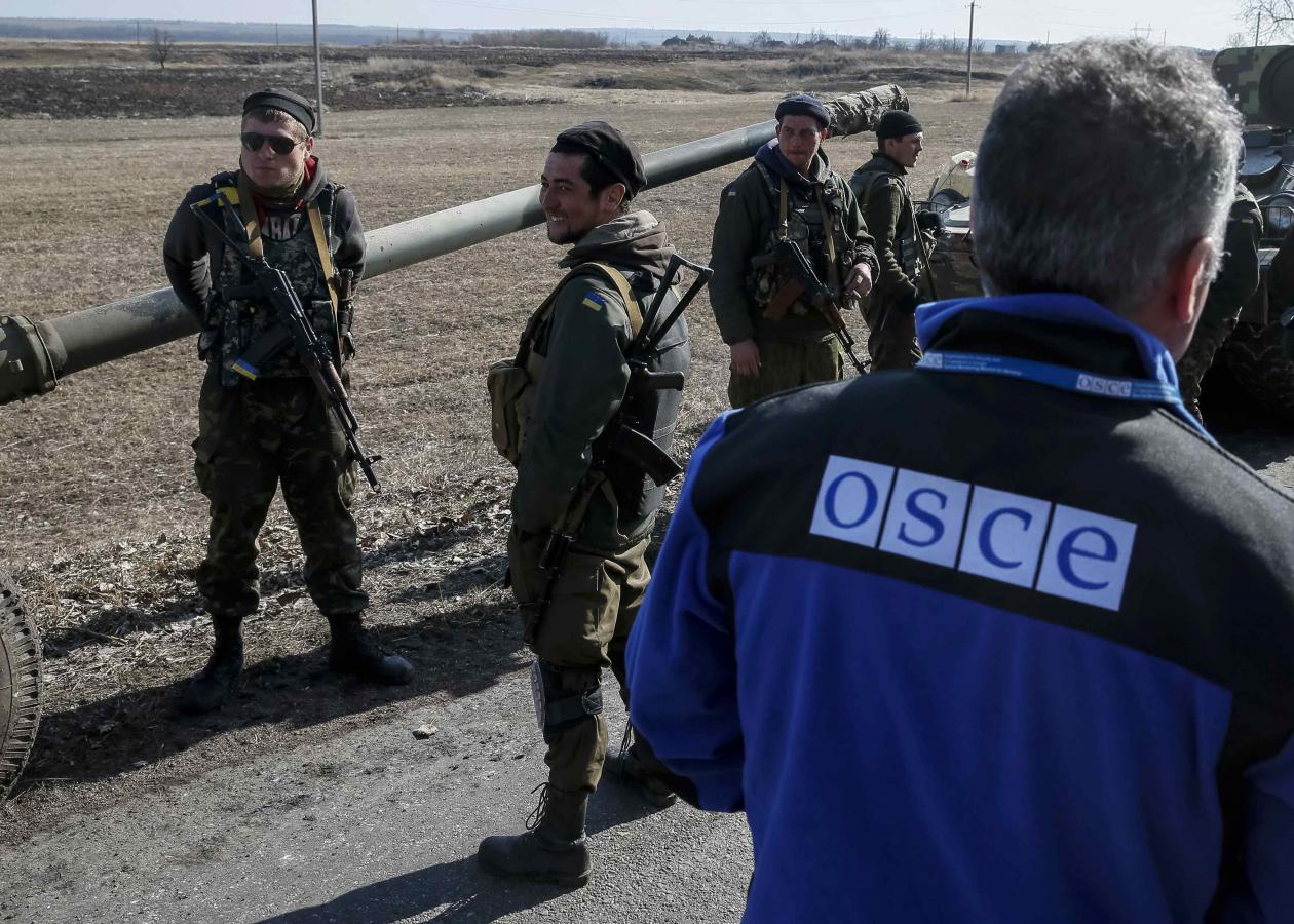 A member of Special Monitoring Mission of the Organization for Security and Cooperation (OSCE) to Ukraine walks along a convoy of Ukrainian armed forces in Blagodatne
