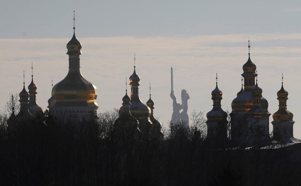 Domes of the Dormition Cathedral of the Kiev Pechersk Lavra monastery are seen in front of the Mother Homeland monument in Kiev